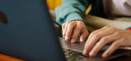 Dłonie na klawiaturze laptopa przy drewnianym biurku, zbliżenie